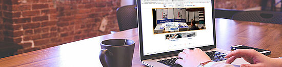 Die Grafik zeigt eine Person, die an einem Laptop auf der Webseite der Otto Brenner Stiftung einen Antrag ausfüllt.